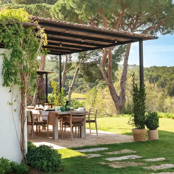 Pérgola con mesa de comedor y jardín de césped con piedras